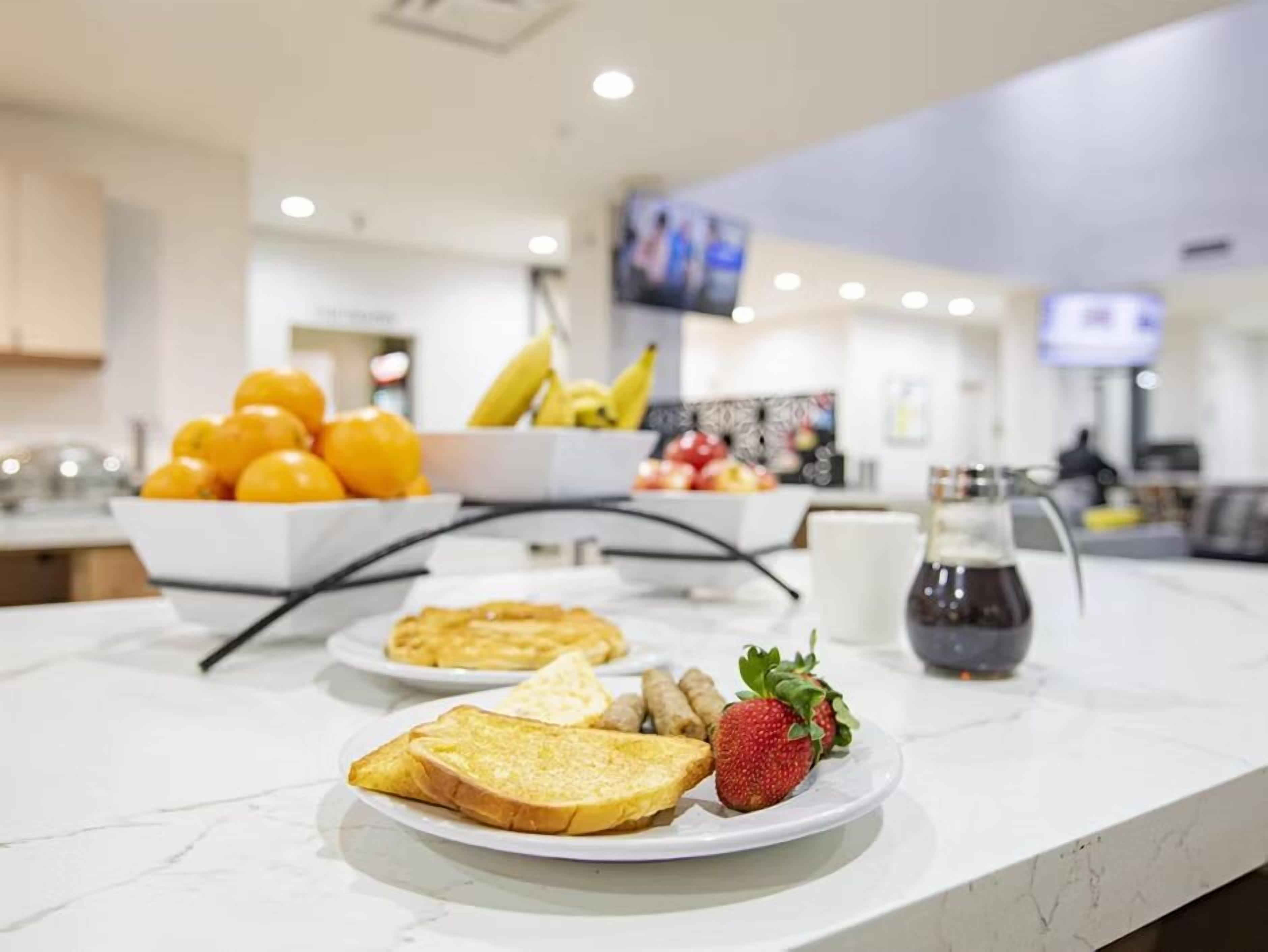 A breakfast buffet with fruits, toast, and a coffee pot.