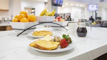 A breakfast buffet with fruits, toast, and a coffee pot.