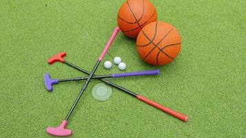 Une surface verte avec un ballon de basket, trois clubs de golf et trois balles de golf.
