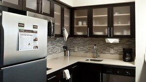 Une cuisine moderne avec des meubles de couleur sombre, des appareils électroménagers en acier inoxydable et un dosseret carrelé.