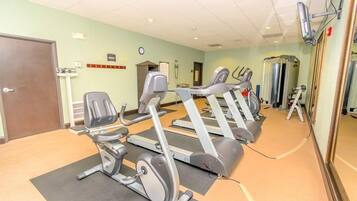 A gym with stationary bikes, a treadmill, and a mirror wall.