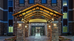 Une entrée d’immeuble avec une façade en pierre, un toit en arc et des fenêtres illuminées.