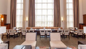 A hotel lobby with a seating area, tables, and chairs arranged for guests. - Queen Studio Suite | Free Breakfast, Pool & Gym (Bowling Green)