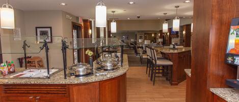 A hotel kitchen with granite countertops, stainless steel appliances, and wooden cabinets.