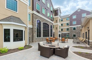 A courtyard with outdoor seating, stone walls, and large windows.