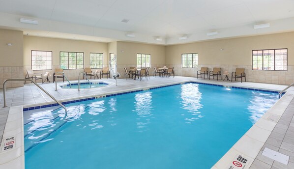 A large indoor swimming pool with multiple lanes, surrounded by lounge chairs and tables.