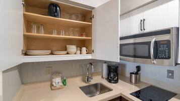A compact kitchen with a microwave, coffee maker, and a sink.