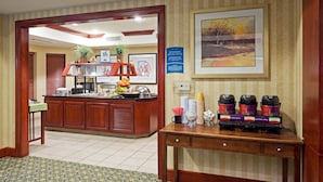 Vestíbulo de hotel con recepción, zona de buffet y estación de café.