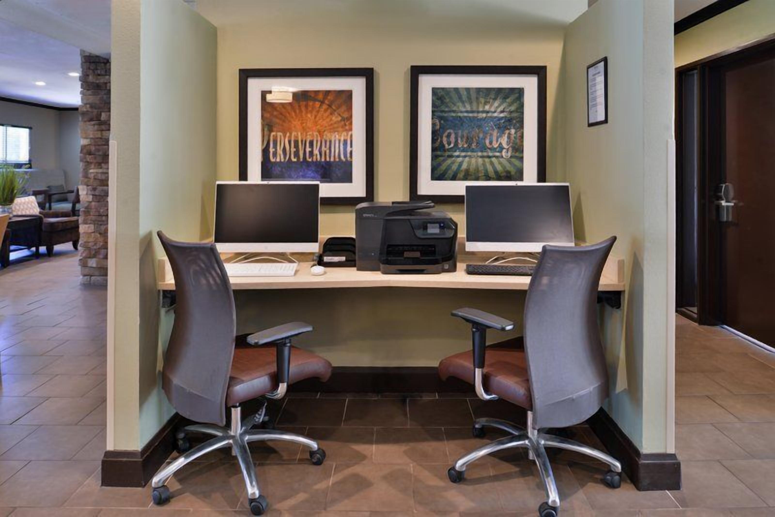 A reception desk with two computer monitors, a printer, and two office chairs.