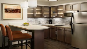 A modern kitchen with a central island, stainless steel appliances, and a tiled backsplash.