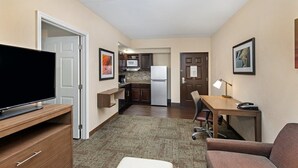A hotel room with a TV, a desk, a chair, a couch, a kitchen area, and a door. - King Suite. Free Breakfast. Pool & Gym. Close to the University of Tennessee Arboretum! (Oak Ridge)