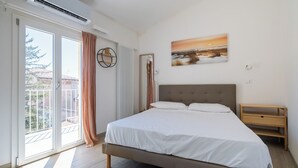 A bedroom with a bed, a nightstand, a wall-mounted air conditioner, a window with curtains, and a painting on the wall. - Appartamento vicino all'Orto Botanico by Wonderful Italy (Bologna)