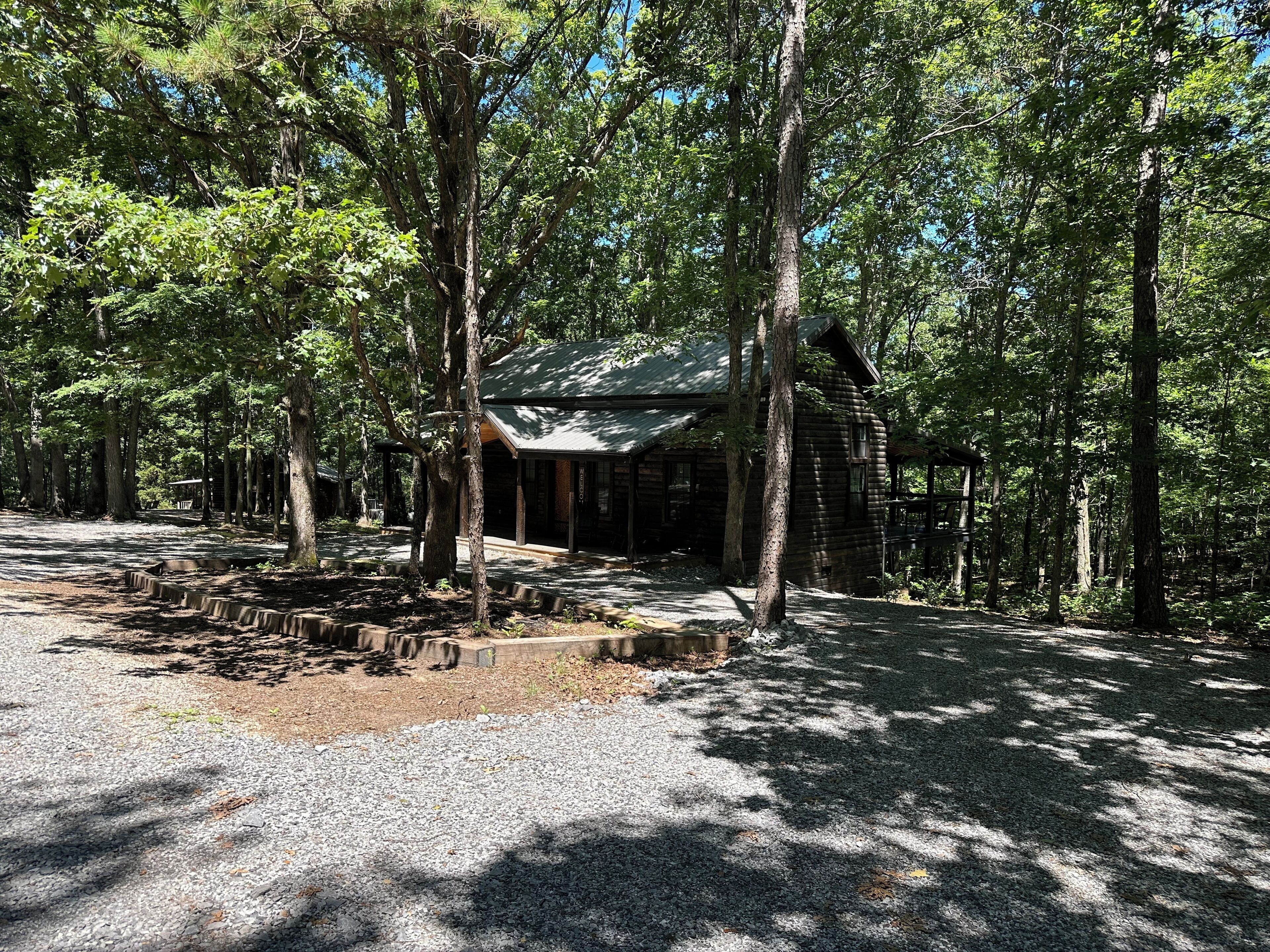 A rustic cabin surrounded by tall trees in a forested area.