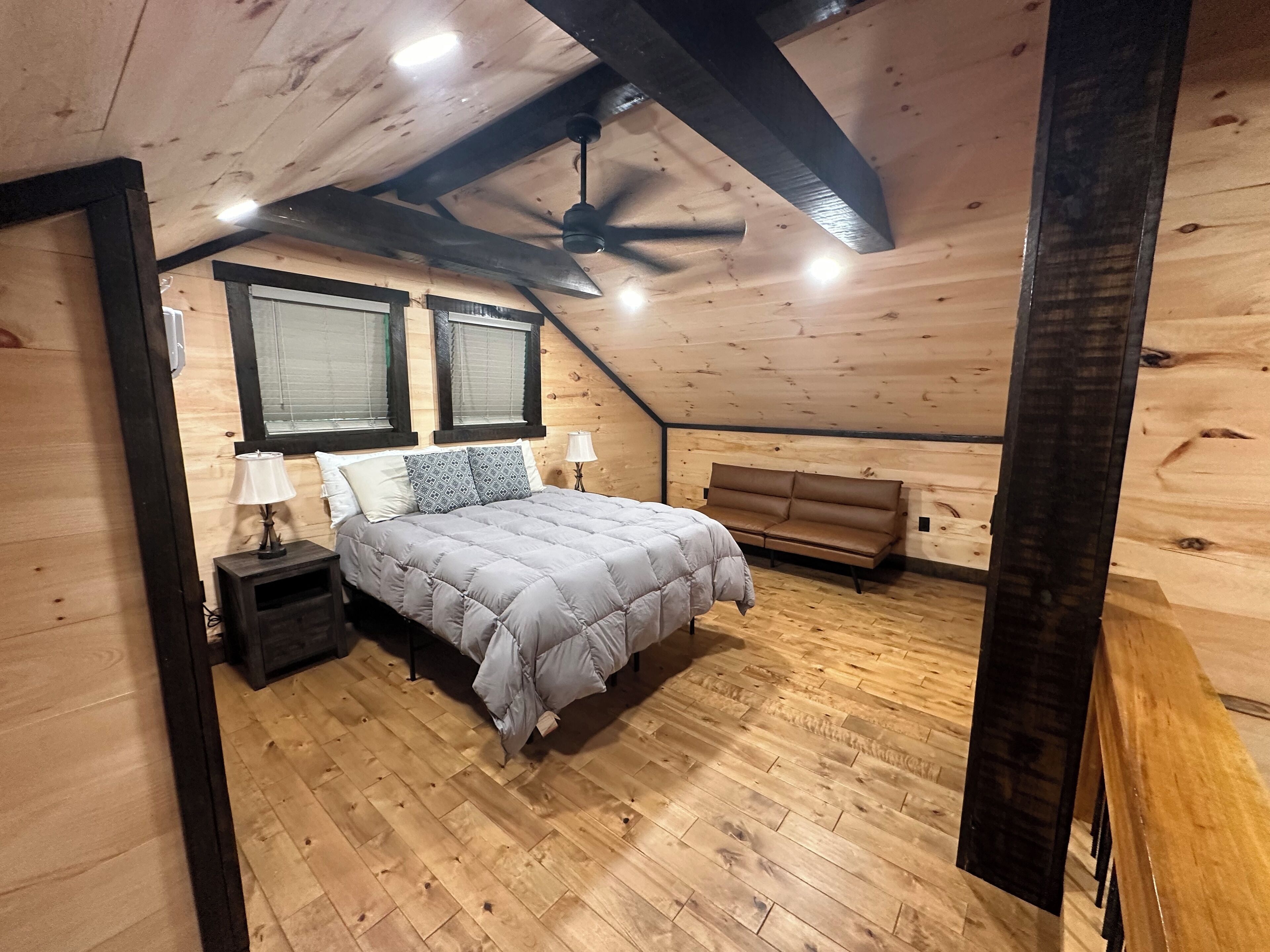 A cozy attic bedroom with a bed, a bench, and a ceiling fan.