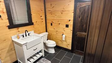A compact bathroom with a white sink, toilet, and wooden walls.