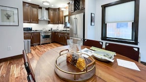 Una cucina moderna con mobili in legno, elettrodomestici in acciaio inox e un tavolo da pranzo con una ciotola di frutta.