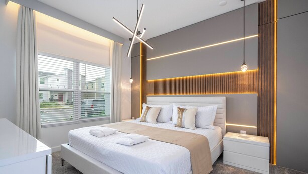 Ein modernes Hotelzimmer mit einem großen Bett, Nachttischen, einem Schreibtisch und Blick ins Freie.