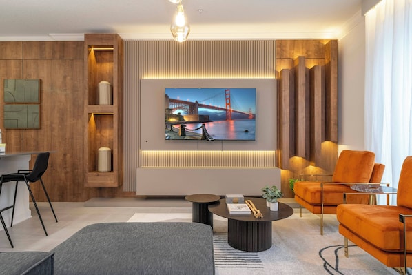 A modern living room with a large TV displaying a bridge, a sofa, a coffee table, and a dining area with chairs.