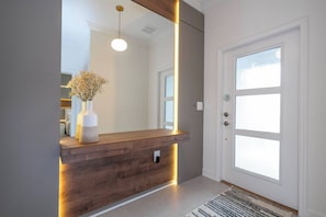 A reception desk with a wooden finish and a vase of flowers, a large mirror above it, and a door with a window.