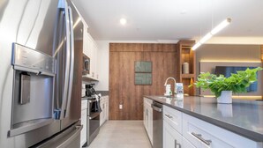 Eine moderne Küche mit Edelstahlgeräten, einer Holz-Akzentwand und einem Blumentopf auf der Arbeitsfläche.