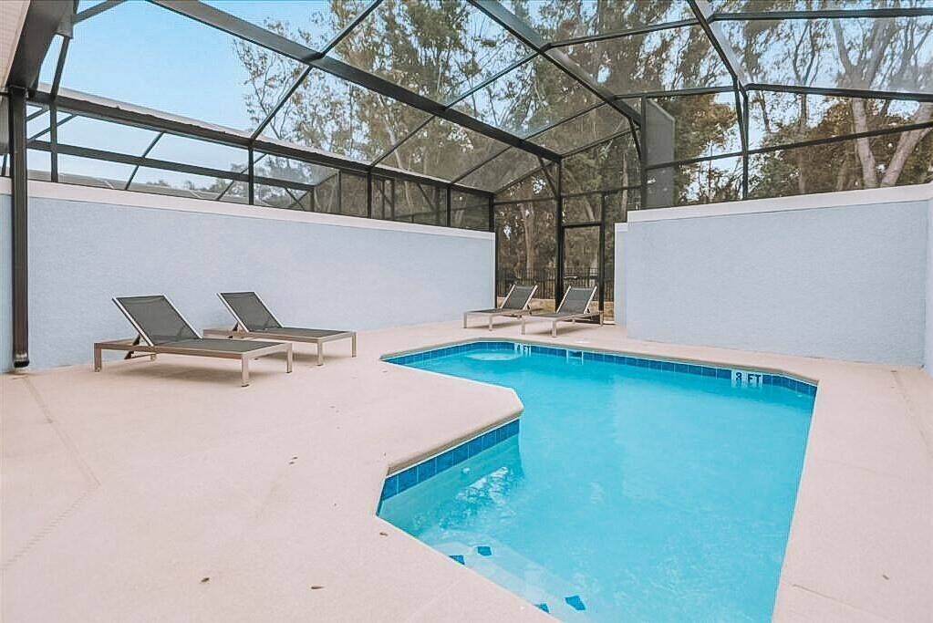 Une piscine intérieure dotée d’un toit en verre, entourée de chaises longues.