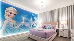 A bedroom with a large wall mural, a bed with purple bedding, a nightstand with a lamp, and a dresser. - Private 4BR Check In and Chill Out (2417ST) (Kissimmee)