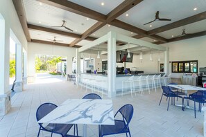 Un amplio patio exterior con zona de bar, mobiliario y ventiladores de techo.