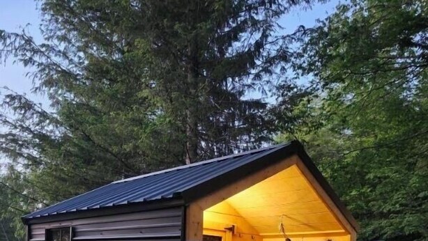 A small wooden cabin with a sloped roof, a single door, and a hammock hanging inside. - Woods I GO 2 Lose my Mind Roscoe (Roscoe)