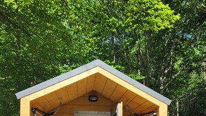 A small wooden cabin with a bench and hammock seating, surrounded by trees. - Woods I GO 2 Lose my Mind Roscoe (Roscoe)