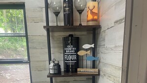 A wooden shelf with wine glasses, a bottle of wine, a candle, and kitchenware. - Woods I GO 2 Lose my Mind Roscoe (Roscoe)