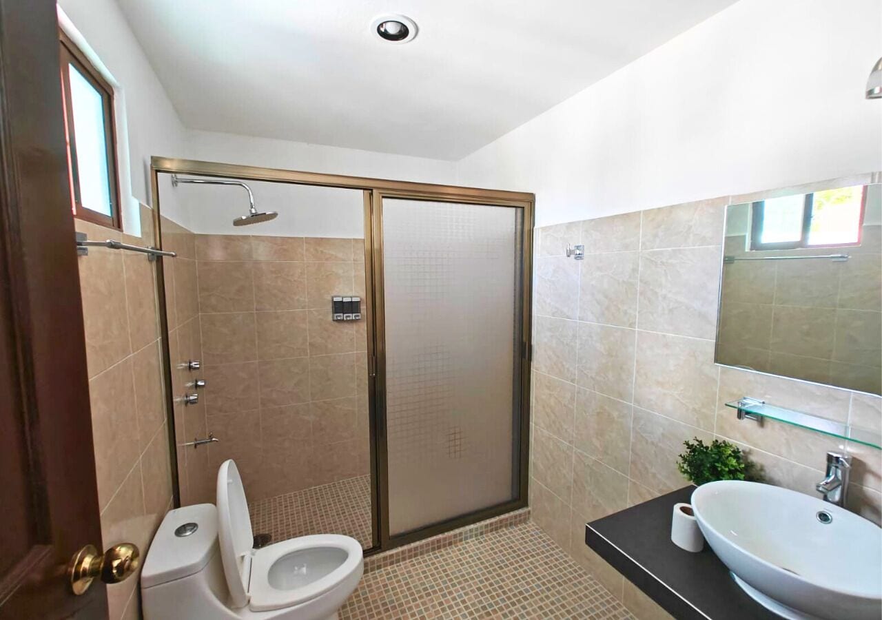 A bathroom with a toilet, a shower with a glass door, and a sink with a mirror above it.