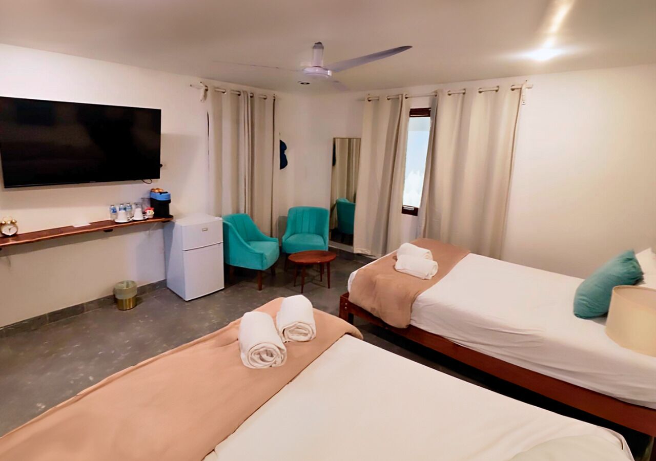Habitación de hotel con dos camas, televisión, escritorio, silla y una mesita.