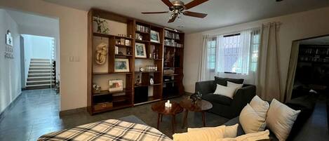 Un salon comprenant un canapé, une table basse, une bibliothèque et un ventilateur de plafond.
