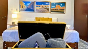 Habitación de hotel con dos camas, un maletero grande en el suelo y tres cuadros en la pared.