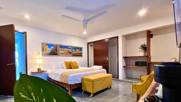 Una habitación de hotel con cama, escritorio, silla, televisión y ventilador de techo.