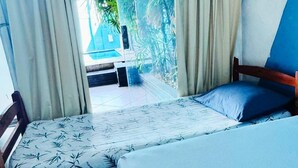 Une chambre avec deux lits, l’un recouvert d’une couvre-lit à motifs et l’autre d’une couvre-lit bleu uni.