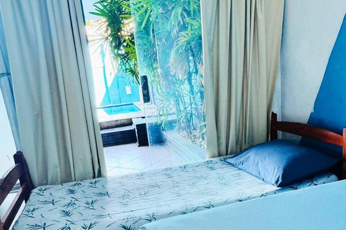 Une chambre avec deux lits, l’un recouvert d’une couvre-lit à motifs et l’autre d’une couvre-lit bleu uni.