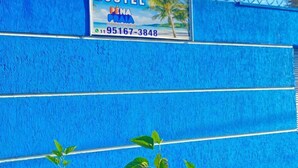 Un mur bleu d’auberge de jeunesse sur lequel est affiché un panneau publicitaire indiquant « AUBERGE PENA » et un numéro de téléphone.