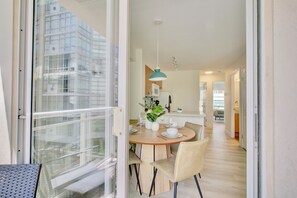 A modern dining area with a round wooden table, beige chairs, and a teal pendant light. - Modern 2-Bed, 2-Bath Urban Oasis in Downtown Vancouver (Vancouver)
