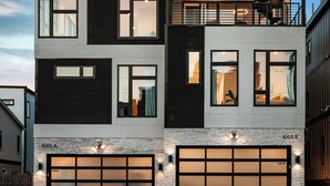 Una casa moderna de dos pisos con garaje, ventanas amplias y un balcón.