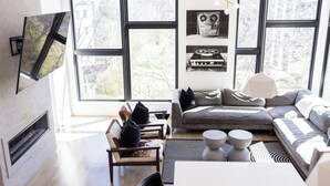 Una sala de estar moderna con chimenea, ventanas amplias, un sofá modular gris y una mesa de centro.