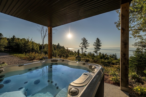 A hot tub with a clear view of the ocean and trees.