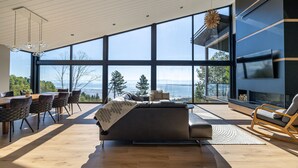 A modern interior with a large dining table, seating, a sofa, and a TV. - Le Lord, River view, trail and snowmobile (Les Éboulements)