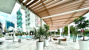 A modern outdoor pool area with a wooden pergola, potted plants, and seating arrangements. - Wanders & Yoo (Panama City)