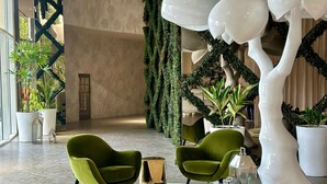 A lobby with two green armchairs, a round table, and a large white tree sculpture. - Wanders & Yoo (Panama City)