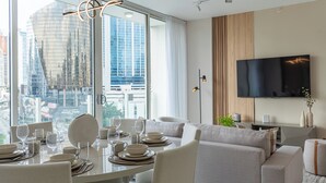A modern living room with a dining area, a sofa, a TV, and a city view. - Wanders & Yoo (Panama City)
