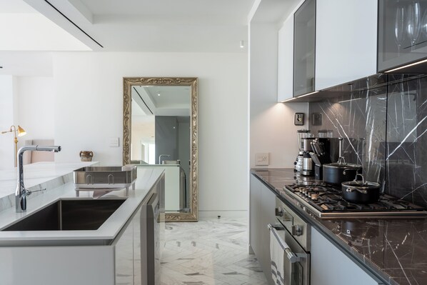 A modern kitchen with a marble countertop, stainless steel appliances, and a large mirror. - Wanders & Yoo (Panama City)