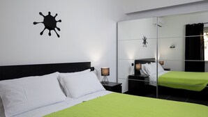 A hotel room with a bed, a nightstand, a lamp, a mirror, and a wall decoration. - Bonaventura's House by Wonderful Italy (Olbia)
