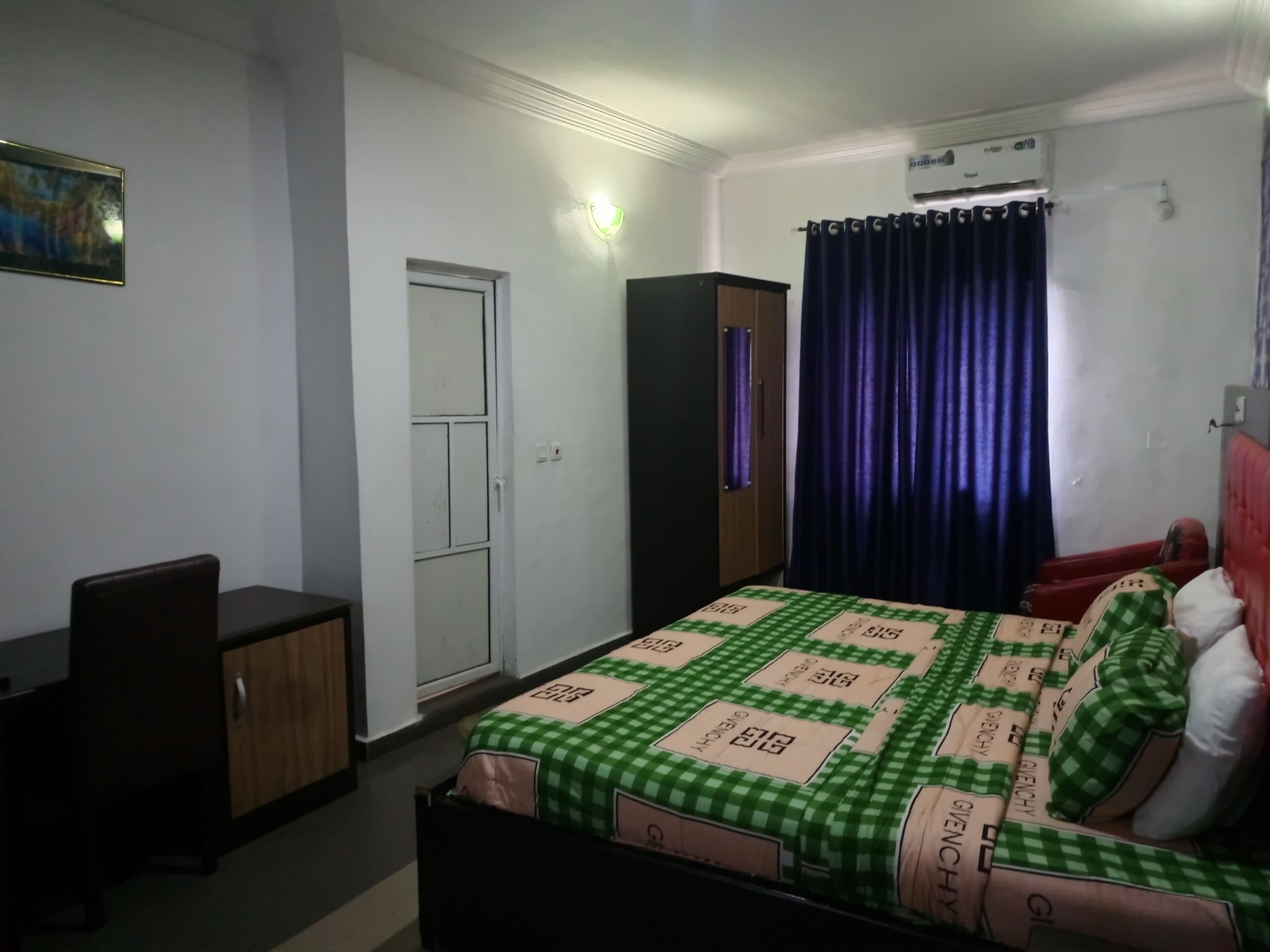 Un dormitorio con cama, armario, escritorio y puerta.
