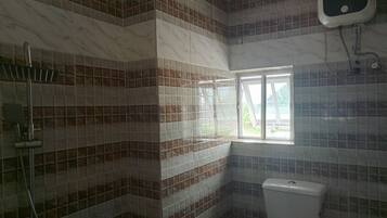 A bathroom with a toilet, a shower, and a window.